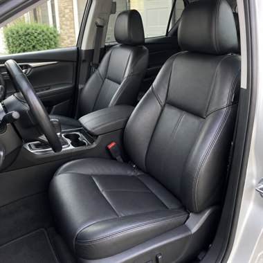 Restored black leather car interior with left-hand-drive steering wheel